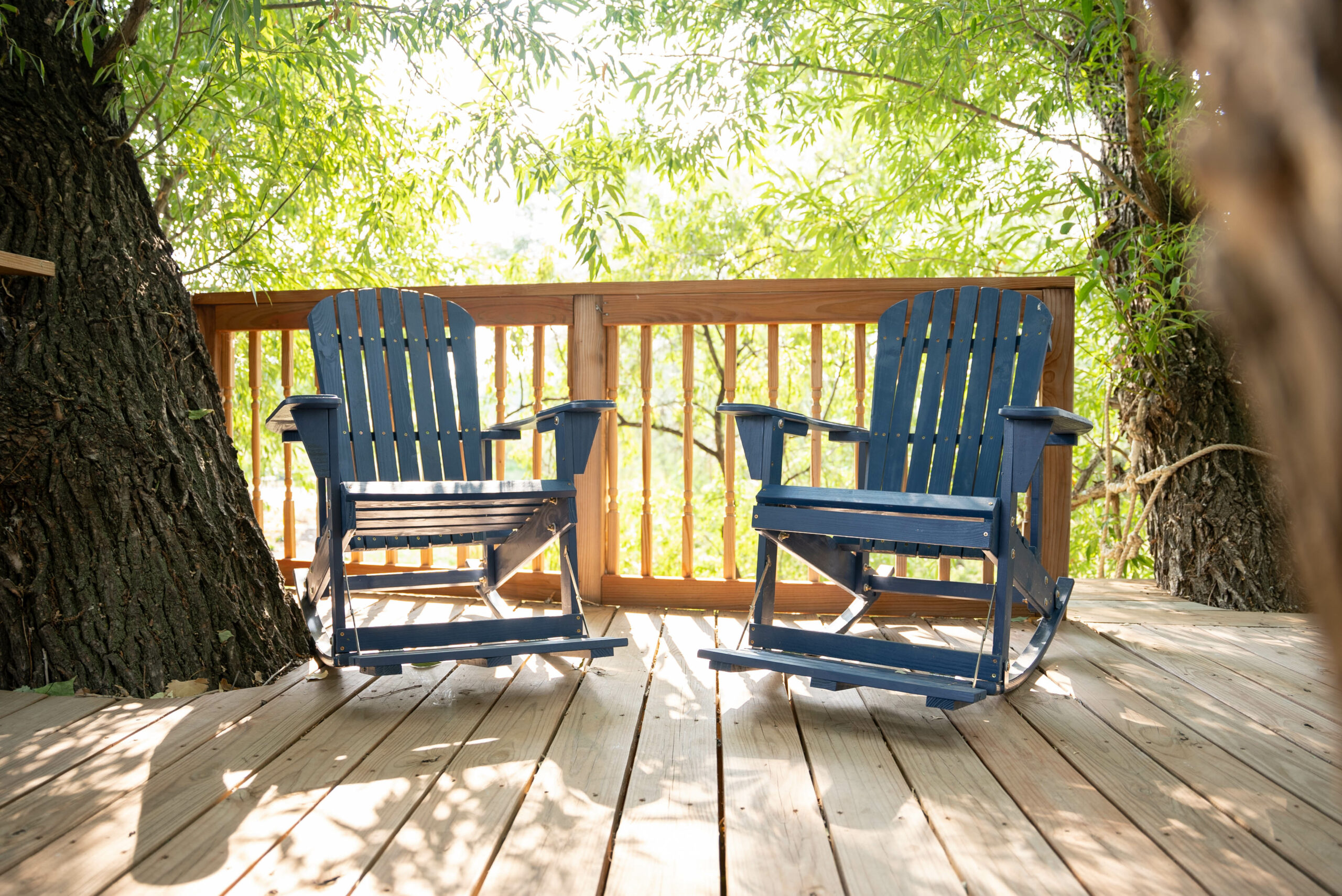 two blue rocking chairs in a treehouse with green leaves