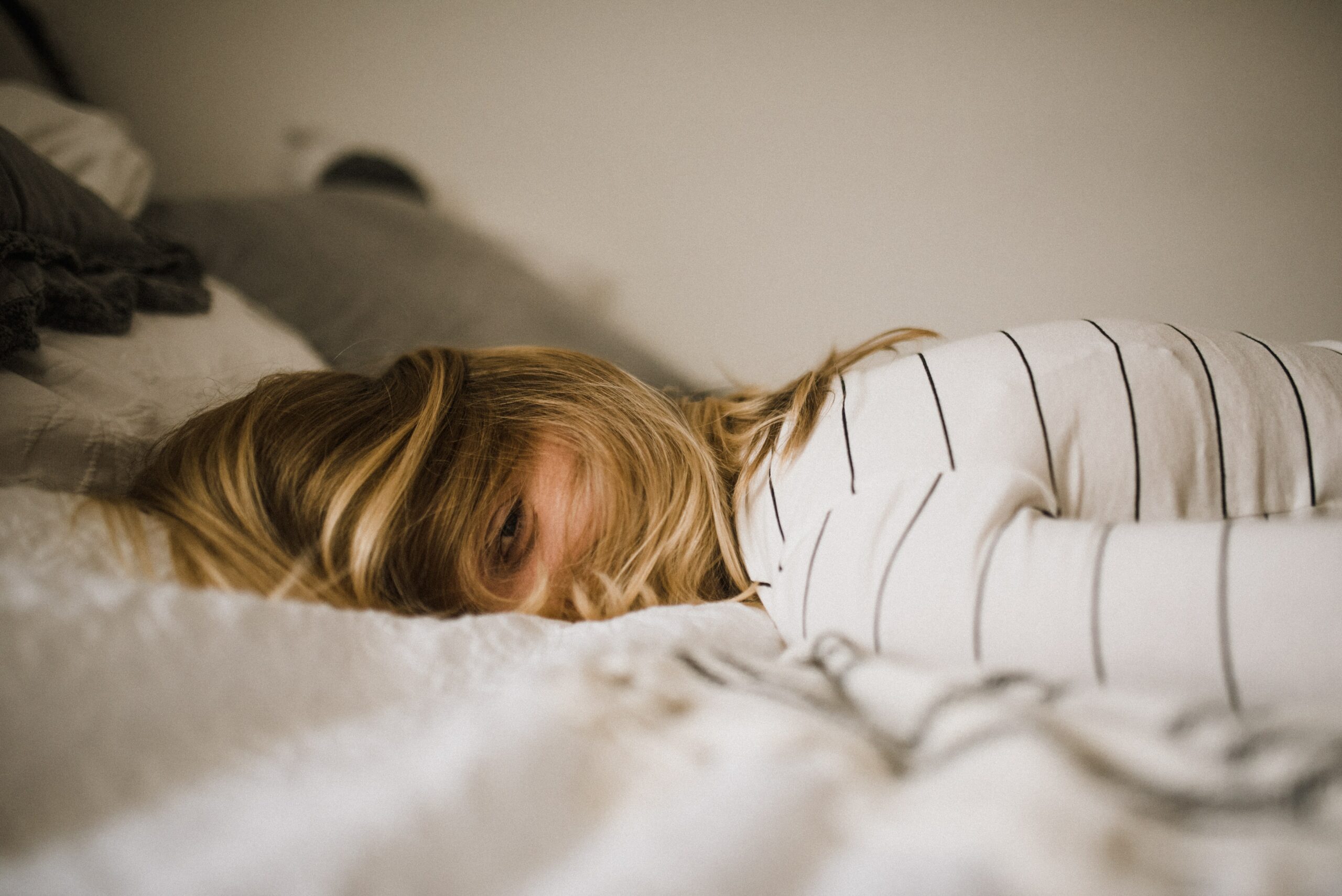 a blonde woman laying face down on a white sheet