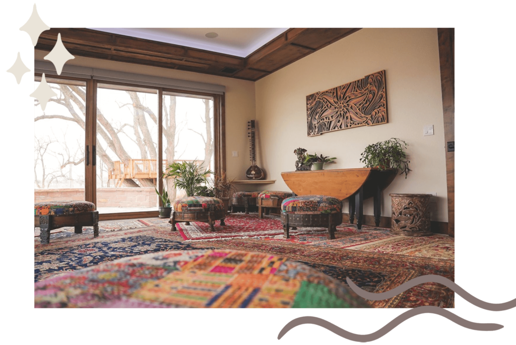 wide shot of a room with layered rugs, large windows, and a wooden art piece on the wall