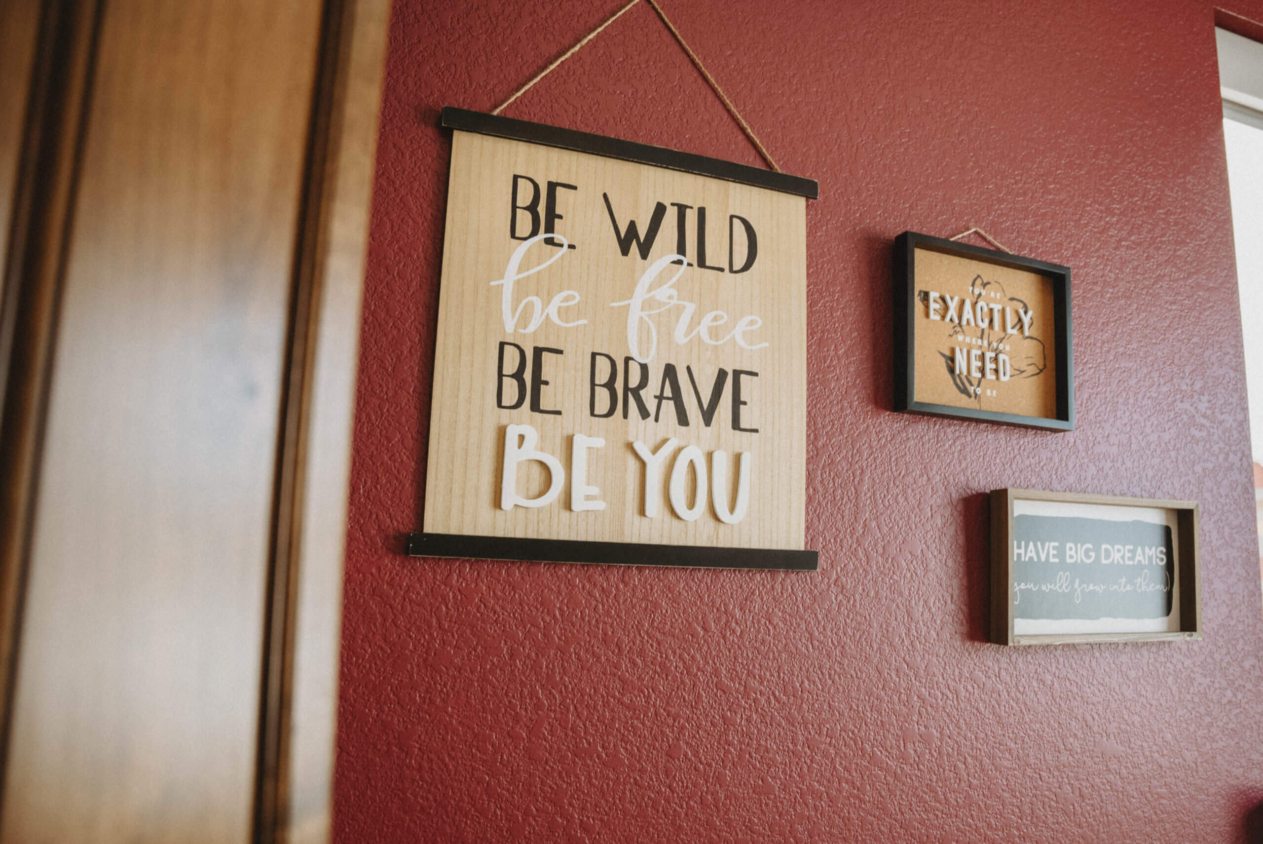 Three hanging signs on a red wall