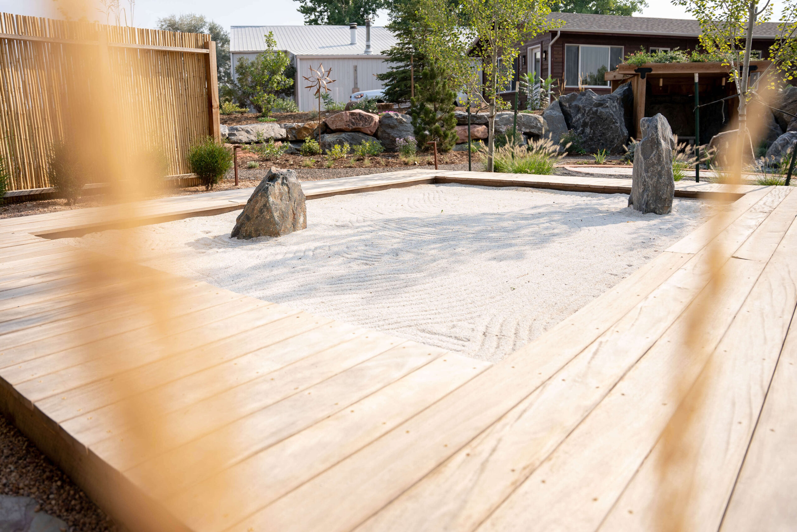 Sand zen garden with two large boulder and wood walk way frame