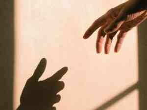 Hand Reaching With Shadow of Hand on Wall