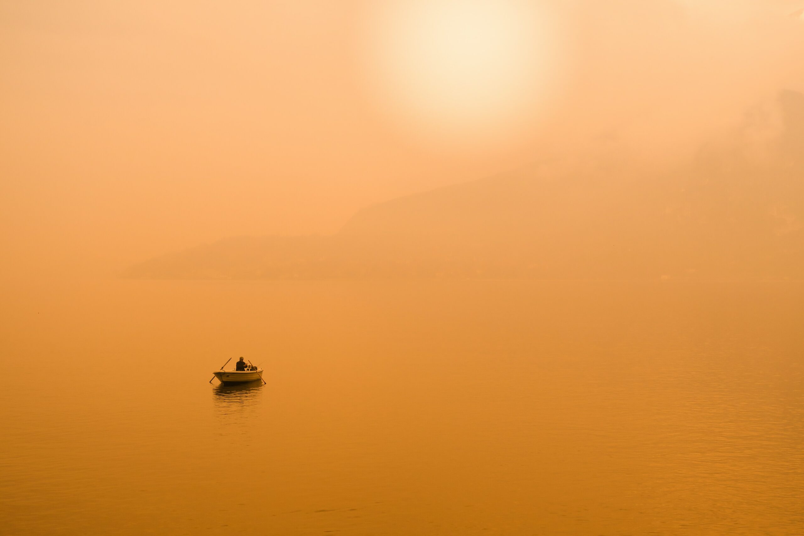 Journal a wide photo of a single boat on still waters at sunset